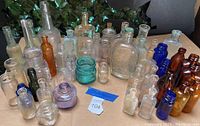 Wide shot of entire assortment of vintage and antique bottles of varying colors and sizes placed on cardboard.