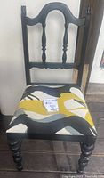 Front view of black wooden side chair with black and mustard greyhound print linen seat, showing turned back spindles and seat upholstery