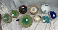 Overview of all ceramic bowls and plates on white cloth background with identification numbers visible