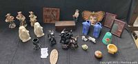 Photo showing entire lot arranged on a black cloth, including figurines, planters, woodcraft boxes, and pottery items.