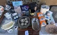 Photo showing assorted kitchen items including silver plated coffee maker, studio pottery plates, new PUR water filters, cutting board with metal strainer, and various glassware and kitchen utensils.