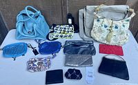 Overall grouping of 12 handbags, pouches, wallets and coin purses on white table