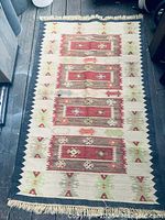 Full view of the rectangular flatweave kilim rug showing overall pattern, colors, and fringe ends.