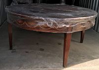 Round mahogany coffee table wrapped in plastic, showing four slender legs and circular top