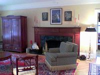 Wide living room view showing rug under armchair, armoire and fireplace
