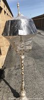 Brass floor lamp wrapped in plastic, full view showing shape and size.
