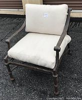 Front view of cast aluminum patio arm chair with off-white cushions showing seat and backrest padding.