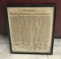 Framed parchment copy of the Declaration of Independence with visible wrinkles inside a simple black frame.