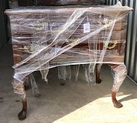 Front view of mahogany chest wrapped in protective plastic