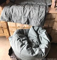 Photo shows sky blue tufted fitted quilt on king size bed and two matching pillow shams on floor, folded.