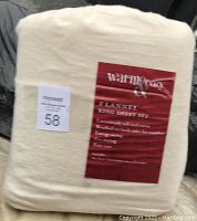 Photo of the full set of Warm & Cozy branded king size flannel sheets in light off-white color, still in original packaging with label showing material and care details.