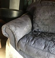 Close-up left arm with rolled design and skirted base showing jacquard floral pattern fabric detail.