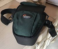 Closed front view of forest green LowePro camera carrying case showing logo and adjustable strap.