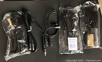 Five video plugs and cables laid flat on a black surface, some sealed in plastic bags lessening exposure, others loosely coiled; cables include power cords, AV cables, and RCA plugs.