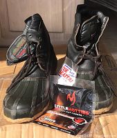 Pair of North Pass boots displayed with a package of handwarmers and toe warmers in front, showing boot upper and lace details.