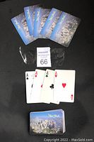 Photo showing five cards fanned with New York City skyline back design and four aces from the card faces arranged below, with some card packaging visible.