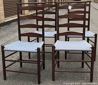 Front view of four chairs grouped together showcasing slat back design and woven seats