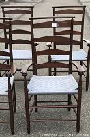 Front row of three and back row of three mahogany-stained slat-back armchairs with colonial blue woven seats arranged outdoors.