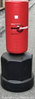 Front view of the red Wavemaster padded cylindrical kicking target attached to the black water-fillable base.