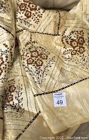 Close-up image of yellow jacquard fabric showing floral and geometric design with brown and black colors.
