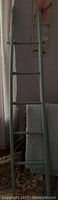 Full view of the antique blanket ladder, showing four horizontal rungs and the tall vertical structure against a wall.