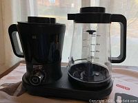 Black DASH iced coffee maker with control knob and glass carafe with measurements.