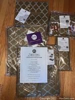 Photo shows multiple sealed storage bins and garment bag with gold and cream patterned fabric, including product literature showing contents.