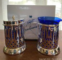 Front view of Avon Royal Sapphire sugar and creamer set with box behind, showcasing cobalt blue glass and silver metal holders