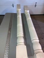Photo showing full length of two painted porch posts with decorative turned sections and flat tops.