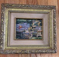 Front view of vintage framed art print showing outdoor patio scene with garden chairs and floral décor.
