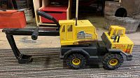 Side view of vintage yellow and black Tonka Turbo Diesel excavator truck showing rust on metal parts and digging arm with hand grips.