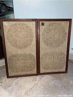 Front view of both speakers showing fabric grills and wood frames