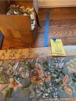 Box filled with various chandelier crystal pieces on floor next to a lot tag labeled 'chandelier crystals'.
