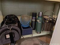 Dog carrier, two thermoses, two ice buckets, and wooden box arranged on shelf