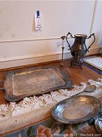 Photo of silver plate serving tray with handles, oval dish, and sterling candlestick with rose detail on wooden table