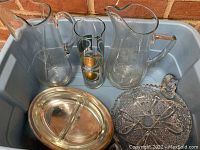 Three clear glass pitchers with etched floral designs, silver plate divided vegetable dish with glass insert, large cut-glass serving dish with handle, all placed in a plastic container.