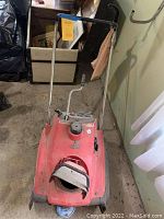 Full view of the Honda HS35 snow blower showing red metal body, black handles, and chute opening.