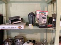 Shelf with boxed hot plate, glass hot plate, popcorn popper box, and glass bowl