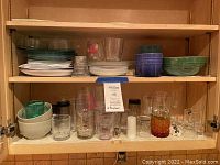 Photo of cupboard shelving with plates stacked on the left and glasses arranged on the right