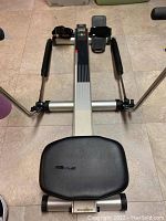 Precor rowing machine seen from seat side with foot pedals and metal frame.