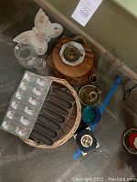 Overview of room decor collection including butterfly serving dish, glass vases, brass candlestick holders, wooden cheese board, cast iron cornbread pan, madeleine baking sheet, blue glass cup, wicker chip basket, coasters.