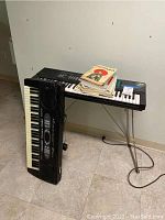 Two electric keyboards leaning and on stand, with sheet music on top