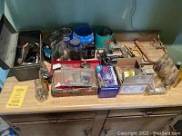 View of assorted tools, bottles, boxes and hardware laid out on a table