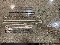 Full view of the necklaces and bracelets laid out on a marble-like surface, showing various colors and materials.