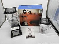 Blendtec Total Blender with two blending canisters, box, and manual displayed on table.