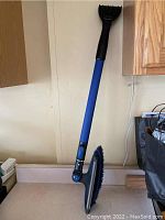 Photo of long blue and black ice remover brush tool standing on kitchen counter