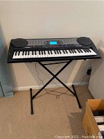 Casio CTK-551 keyboard on black X-style stand with power cord attached