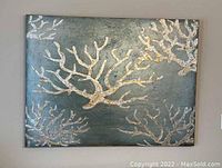 Full view of the large rectangular wall art with aqua background and light gold coral design.