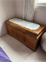 Full view of burled cedar chest with embroidered runner on top