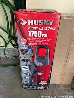 Front view of the red and black Husky 1750 PSI power washer inside original box showing product image and text in Spanish.